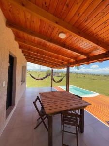 einen Holztisch und Stühle auf einer Terrasse mit Hängematte in der Unterkunft La agreste in Villa Yacanto