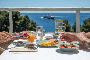 Eine Gruppe von Menschen, die an einem Tisch sitzen und Essen essen. in der Unterkunft Ikion Eco Boutique Hotel in Patitiri