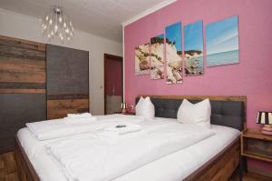 a bedroom with a large white bed with a pink wall at Ferienhus Baabe FeWo 02 Terrasse, gratis Nutzung vom AHOI Erlebnisbad und Sauna in Sellin in Baabe +24 photos