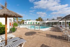 a resort with a swimming pool with chairs and umbrellas at Apartamentos LIVVO Las Gaviotas in Puerto del Carmen