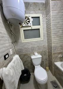 a bathroom with a toilet and a window and a sink at Sunset of Thebes Pyramids View in Cairo