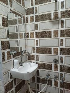 a bathroom with a sink and a tiled wall at GAYATRI SHRADDHALU NIWASs in Ayodhya +12 photos