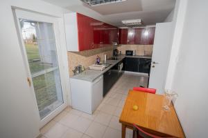 a kitchen with red cabinets and a wooden table at Ipoly Velo Vendégház in Slovenské Ďarmoty