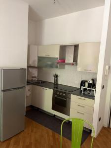 a kitchen with stainless steel appliances and a green stool at Cozy Green Apartment Tardini, Parma in Parma