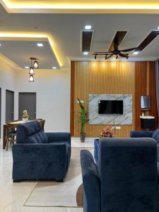 a living room with two blue couches and a tv at Nurul Ain Homestay, Nearby Kelulut Beach, Marang in Marang