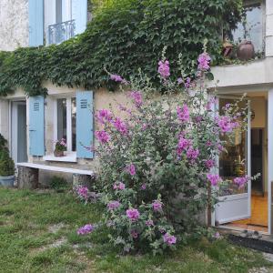 a house with pink flowers on the side of it at La maison de Tina in Leugny