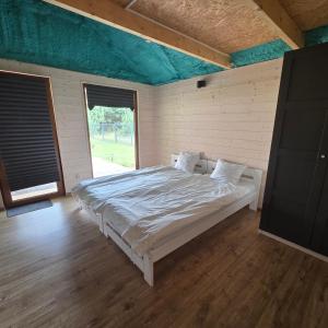 Un dormitorio con una cama y una ventana grande. en Domki Letniskowe Między Jeziorami w Lipnicy, en Lipnica