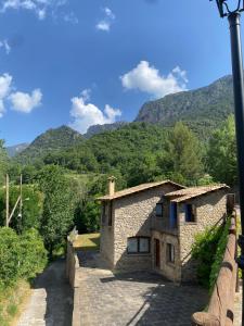 a stone house on a bridge with mountains in the background at Casa Cal Gansoleta in La Coma i la Pedra