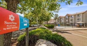 a sign in front of a building with a street sign at SureStay Plus Hotel by Best Western Rocklin in Rocklin