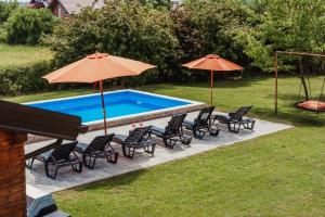 a group of chairs and umbrellas next to a pool at Kuća za odmor Dugo Selo M&A in Dugo Selo