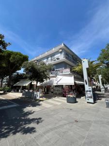 a large building with tables and umbrellas in front of it at Hotel Zen in Lignano Sabbiadoro