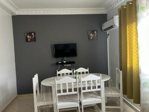 a dining room with a table and chairs and a television at Beau appartement à saidia in Saïdia