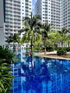a large swimming pool with palm trees and buildings at SLY Staycation at Shore Residences Mall of Asia in Manila