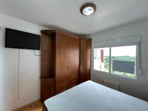 a bedroom with a bed and a cabinet and a television at Gramado Village Apartamento no Centro in Gramado +11 photos