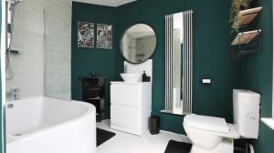 a bathroom with a white toilet and a green wall at Modern 2 bed house in Enfield with private driveway parking in Brimsdown Station +9 photos