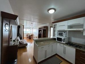 a kitchen with white cabinets and a counter top at Gramado Village Apartamento no Centro in Gramado