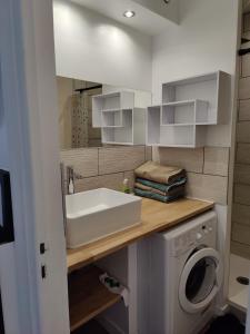 a bathroom with a sink and a washing machine at T4 coeur de ville, à deux pas de la plage - 3 chambres in Saint-Nazaire