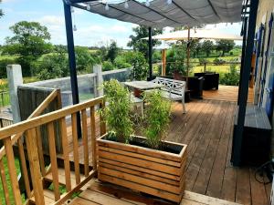 a wooden deck with a table and an umbrella at Le pas de deux in Brigueuil-le-Chantre