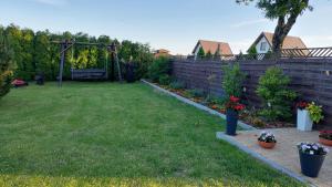 a backyard with a fence and some flowers in a yard at Apartament na Górce in Mikołajki +7 photos