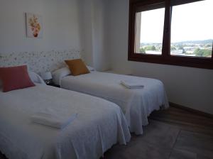 two beds in a room with a window at LAR SANTIAGO Apartamentos y Dúplex - Parejas, Familias y Peregrinos in Santiago de Compostela