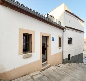 a white building with two windows and a door at Torre de la Yerba in Cáceres