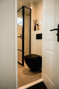 a bathroom with a black toilet in a room at Veluwse Wellness Lodge Selina in Ermelo +27 photos