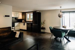 a living room with a couch and a table and a kitchen at Veluwse Wellness Lodge Selina in Ermelo