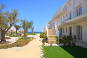 a building with stairs and green grass next to the ocean at Acquamarina in Pachino