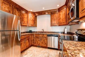a kitchen with wooden cabinets and a stainless steel refrigerator at Ski Hill 15 by Ski Country Resorts in Breckenridge +3 photos