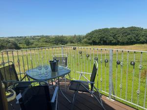 a table and chairs on a balcony with a view at Hayes Lodge Coach House in Chulmleigh