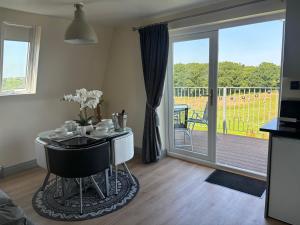 a dining room with a table and a sliding glass door at Hayes Lodge Coach House in Chulmleigh