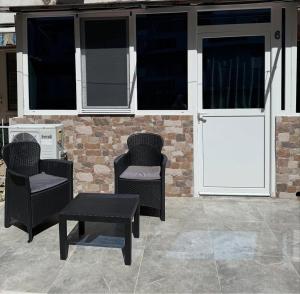 a patio with two chairs and a table and windows at Vaso apartman Bečići in Boreti