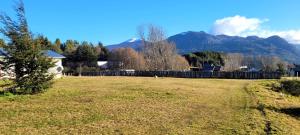 a field with a fence and mountains in the background at Parcela Yolanda en Alto Baguales in Coihaique