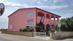 a pink building with a sign on the side of it at Apartmani Trputec, otok Vir in Vir