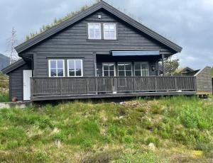 a black house with a deck on a hill at Modern, lovely holidayhome, in quiet nature close to Trolltunga in Utsikten