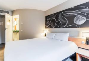 a bedroom with a white bed and a painting on the wall at B&B HOTEL Thionville Yutz Route du Luxembourg in Basse-Yutz
