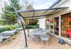 バッス・ユッツにあるB&B HOTEL Thionville Yutz Route du Luxembourgのパティオ(日焼け止めの下のテーブルと椅子付)