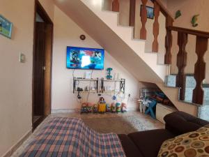 a living room with a couch and a tv on the wall at Casa ampla Churrasqueira Natureza Maricá RJ in Maricá