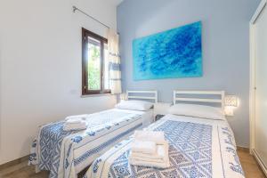 two beds in a room with blue walls at Villa Bouganville Cala Sinzias in Castiadas