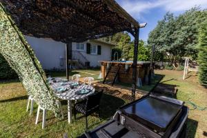 un patio trasero con mesa, sillas y parrilla en Gite west landes, en Onesse-et-Laharie