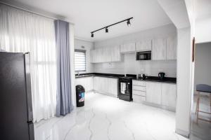 una cucina con armadietti bianchi ed elettrodomestici neri di Longhorn Ibex Apartments a Lusaka Altre 11 foto