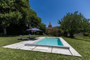a swimming pool in a yard with an umbrella at Gîte des granges in Fargues
