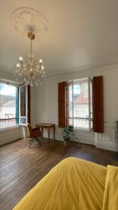 une chambre avec un lustre, une table et des fenêtres dans l'établissement Suite privative au Domaine des Étoiles du Gâtinais, à La Celle-sous-Gouzon