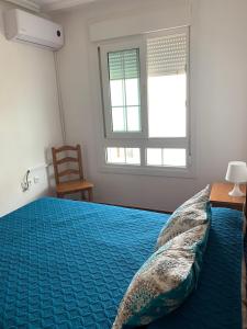 a bedroom with a blue bed with a chair and a window at Apartamentos La Almadraba 1-5 in El Pozo del Cabo