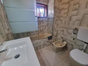 un bagno con un water, una vasca e un lavandino di Zinha's Guest House a Moledo