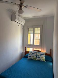 a bedroom with a blue bed with a ceiling fan at Apartamentos La Almadraba 1-5 in El Pozo del Cabo