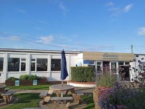 Ein blauer Sonnenschirm steht auf einem Picknicktisch vor einem Gebäude. in der Unterkunft Tranquil 3Bedroom Caravan Pets stay Free in Hunstanton