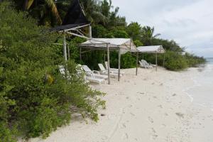 a group of chairs and umbrellas on a beach at Stay Kora in Thinadhoo