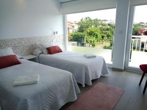 a bedroom with two beds and a large window at LAR JARDÍN - Casas con parking privado in Santiago de Compostela +34 photos