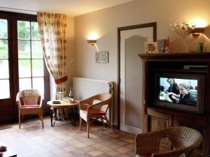 un soggiorno con TV, tavolo e sedie di Holiday home for 10 people set in castle grounds a Barvaux-Condroz